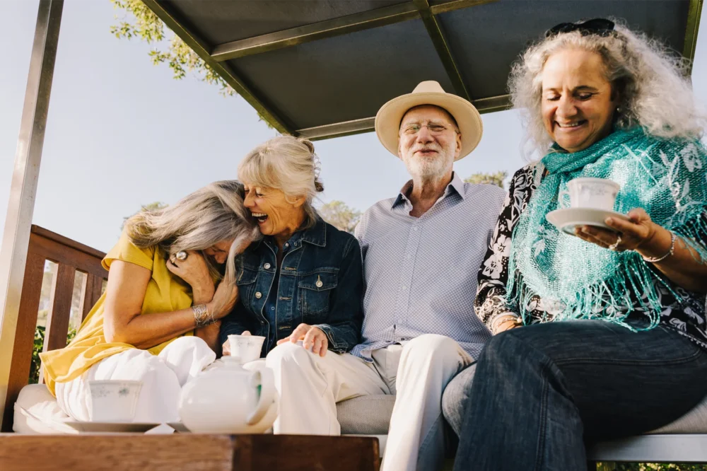A group of happy seniors talking, laughing and drinking tea